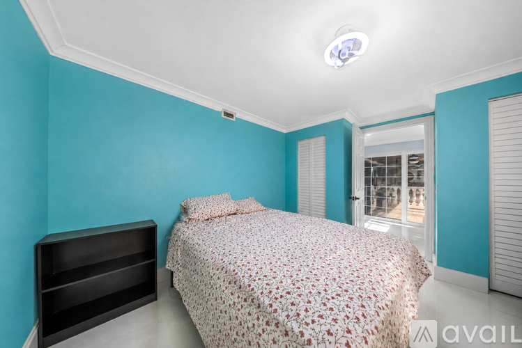 A bedroom with a bed and a black headboard against a blue wall.