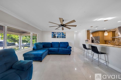 A living room with a blue couch and a ceiling fan.