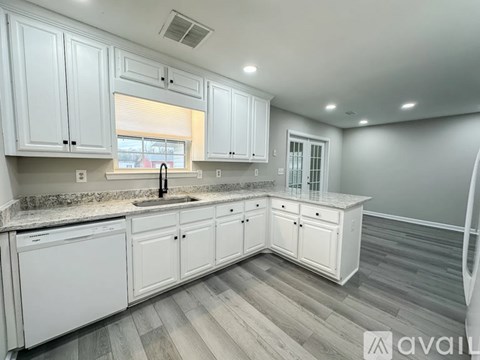 A kitchen with white cabinets and a marble countertop.