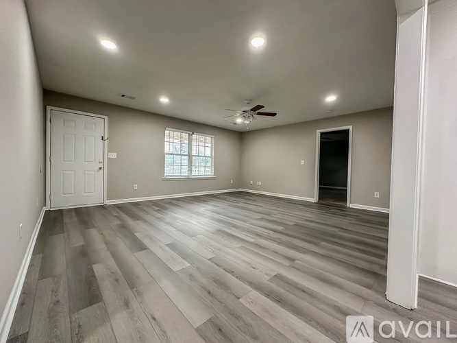 A spacious room with wooden flooring and a ceiling fan.