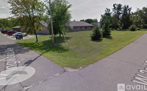 A parking lot with a grassy area and a building in the background.