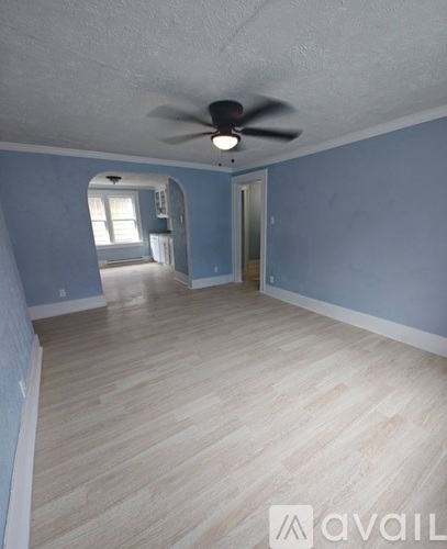 A room with a ceiling fan and light fixture, and a door leading to another room.