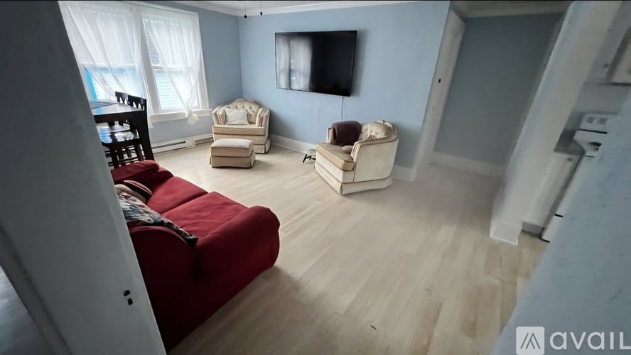 A living room with a red couch and a television on the wall.