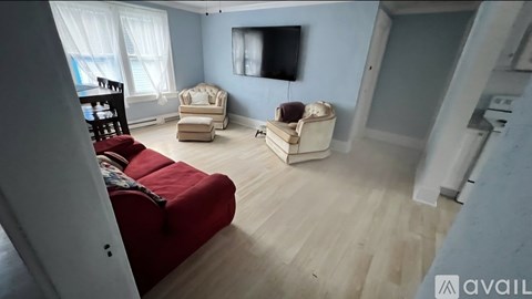 A living room with a red couch and a television on the wall.