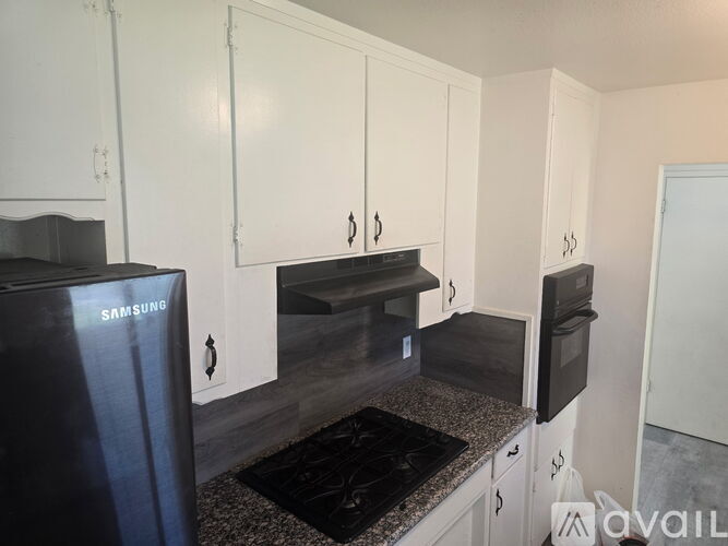 A kitchen with white cabinets and a black stove top.