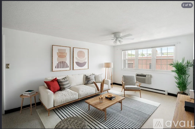 A living room with a white couch, a wooden coffee table, and two chairs.