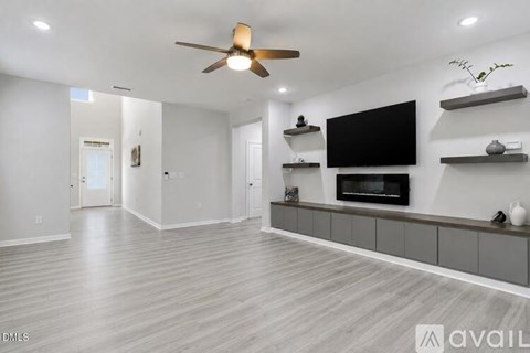 A spacious living room with a television and a ceiling fan.