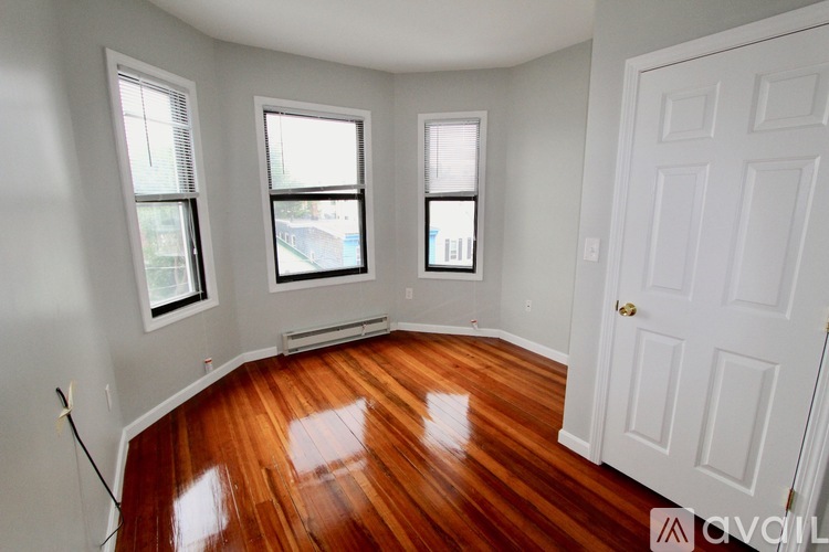 A room with a white door and two windows with wooden floors.