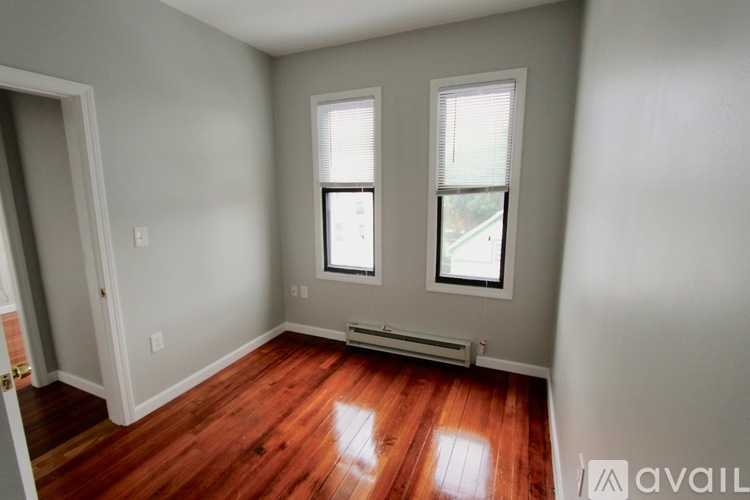 A room with two windows and a wooden floor.