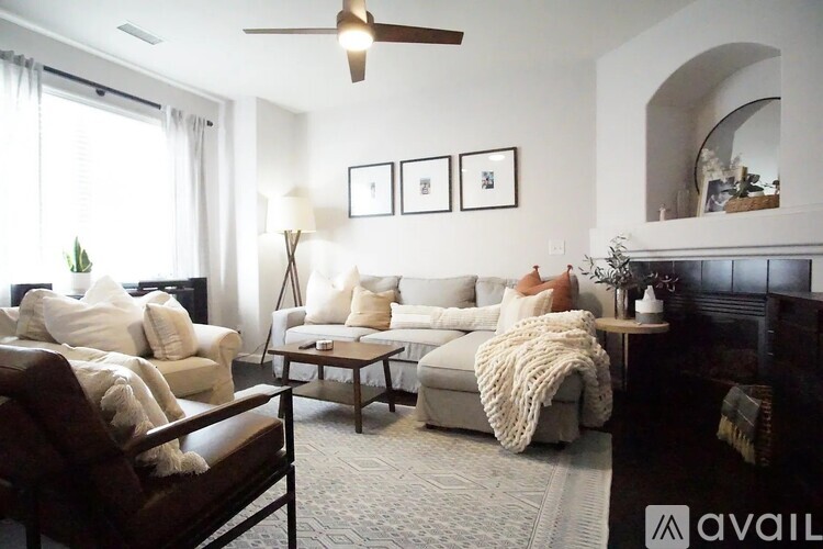 A woman is sitting on a couch in a living room with a fireplace and a ceiling fan.
