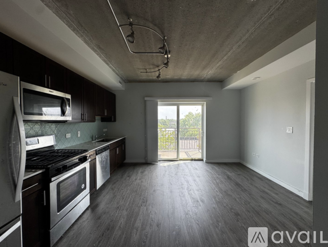 A kitchen with dark wood floors and stainless steel appliances.