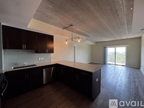 A kitchen with dark wood cabinets and a concrete ceiling.