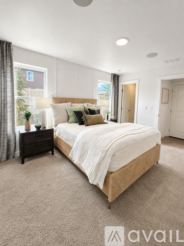 A bedroom with a large bed and a window with curtains.