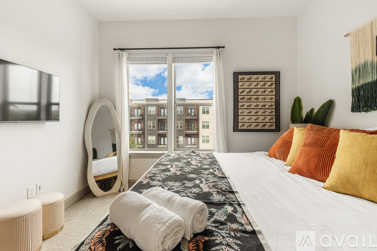 A bedroom with a large bed and a view of a cityscape through the window.