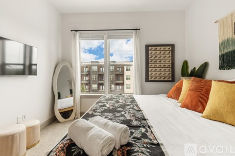 A bedroom with a large bed and a view of a cityscape through the window.