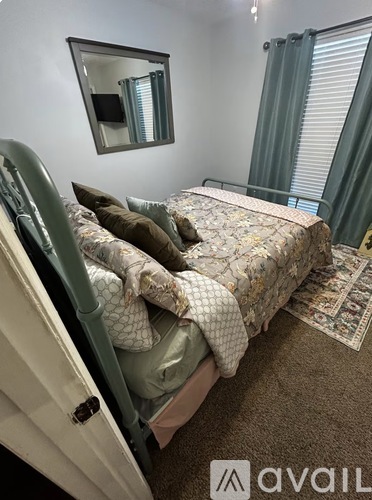 A bedroom with a bed, pillows, and a mirror on the wall.