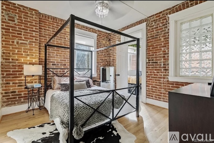 A bedroom with a four poster bed and a brick wall.