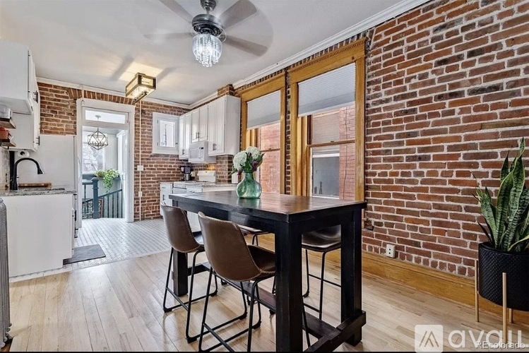 A kitchen with a brick wall and a table with chairs.