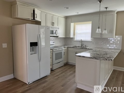 A kitchen with a white refrigerator and a granite countertop.
