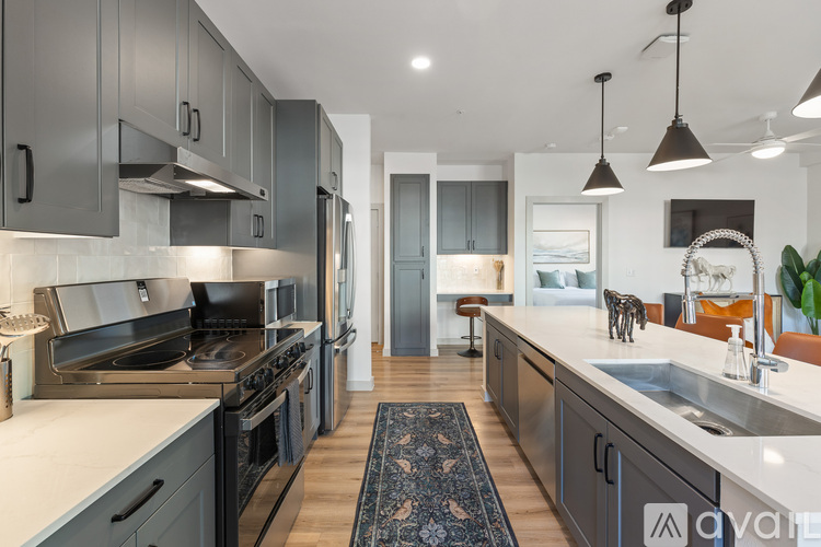 A modern kitchen with dark grey cabinets and stainless steel appliances.