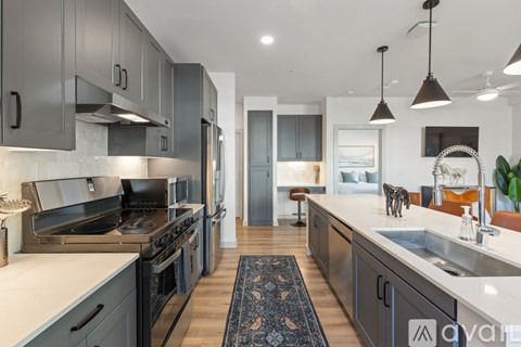 A modern kitchen with dark grey cabinets and stainless steel appliances.