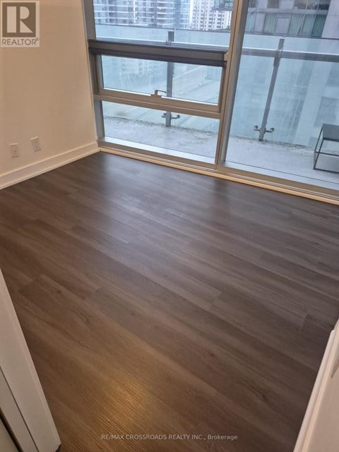 A room with wooden flooring and a glass door leading to a balcony.
