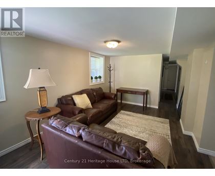 A brown leather couch in a living room with a lamp on a side table.