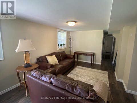 A brown leather couch in a living room with a lamp on a side table.