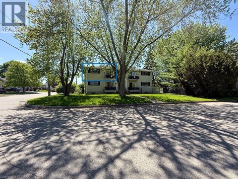 A house with a blue frame is surrounded by trees and grass.