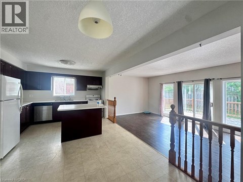A kitchen with a refrigerator, sink, and a dining area with a table and chairs.