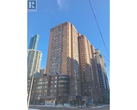A tall brown building stands in front of a glass skyscraper.