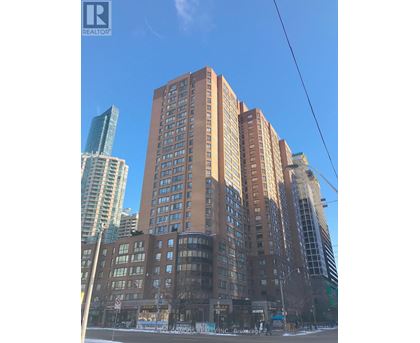 A tall brown building stands in front of a glass skyscraper.
