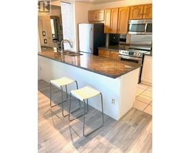A kitchen with a granite counter top and white stools.