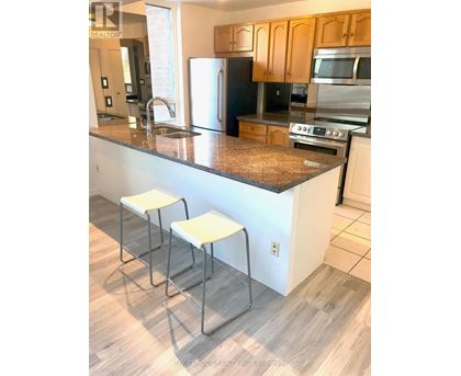 A kitchen with a granite counter top and white stools.