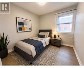 A bedroom with a bed, nightstand, and a painting on the wall.