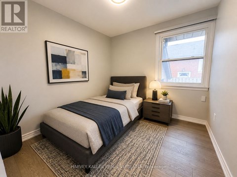 A bedroom with a bed, nightstand, and a painting on the wall.