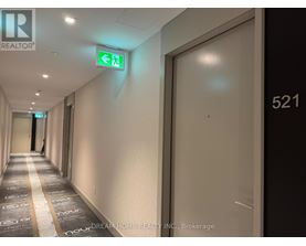 A hallway with a green exit sign and a door with the number 521 on it.