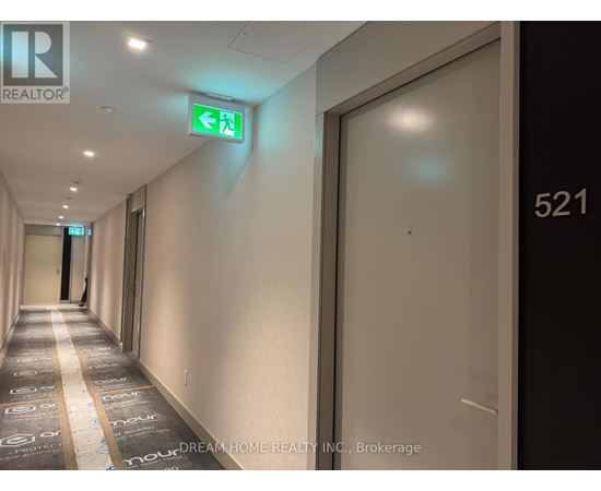 A hallway with a green exit sign and a door with the number 521 on it.