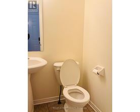 A white toilet in a bathroom with a sink to the left.