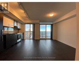 A spacious room with a kitchen area and sliding glass doors leading to a balcony.