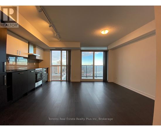 A spacious room with a kitchen area and sliding glass doors leading to a balcony.