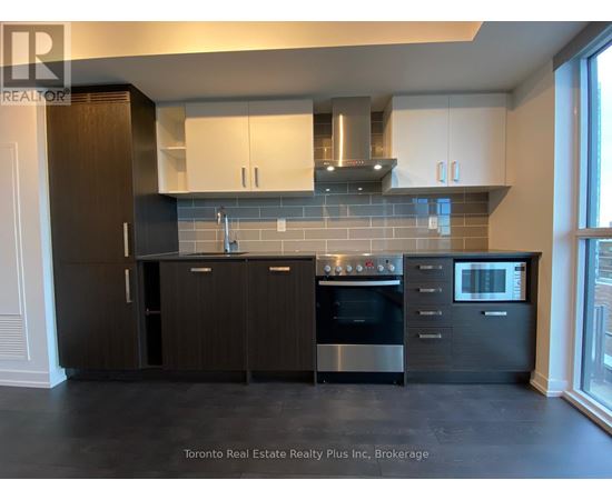 A modern kitchen with dark wood cabinets and stainless steel appliances.