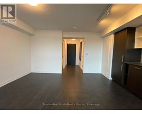 A spacious room with wooden flooring and white walls, with a doorway leading to another room.