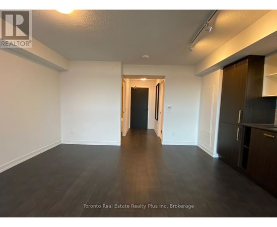 A spacious room with wooden flooring and white walls, with a doorway leading to another room.