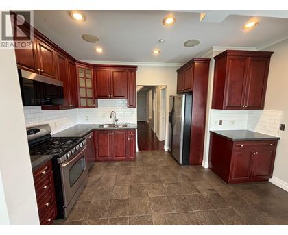A kitchen with brown cabinets and a black stove top oven.