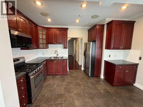 A kitchen with brown cabinets and a black stove top oven.