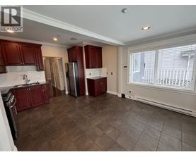 A kitchen with dark wood cabinets and a white backsplash.