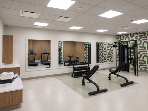 A gym with a variety of equipment including treadmills, weights, and exercise machines.