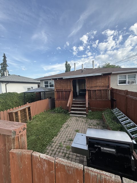 A backyard with a wooden fence and a grill.