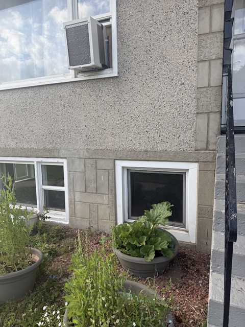 A wall with a window and a planter.